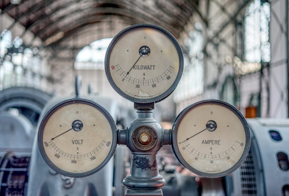 Close-up of vintage volt, ampere, and kilowatt gauges in an old industrial setting.