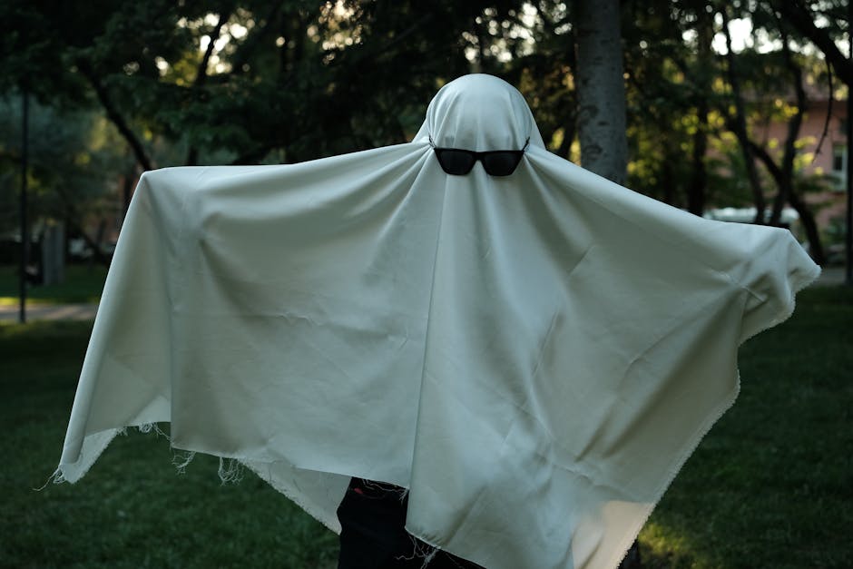 Ghost costume with sunglasses in a park setting, capturing a playful Halloween theme.