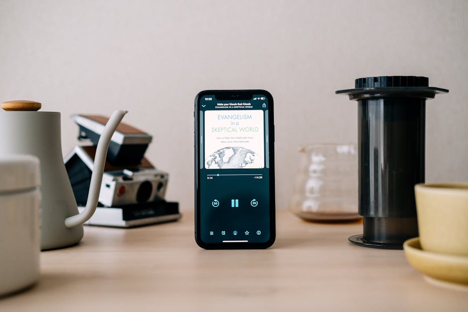 Smartphone displaying content surrounded by coffee brewing equipment on a wooden table. Minimalist and modern setup.