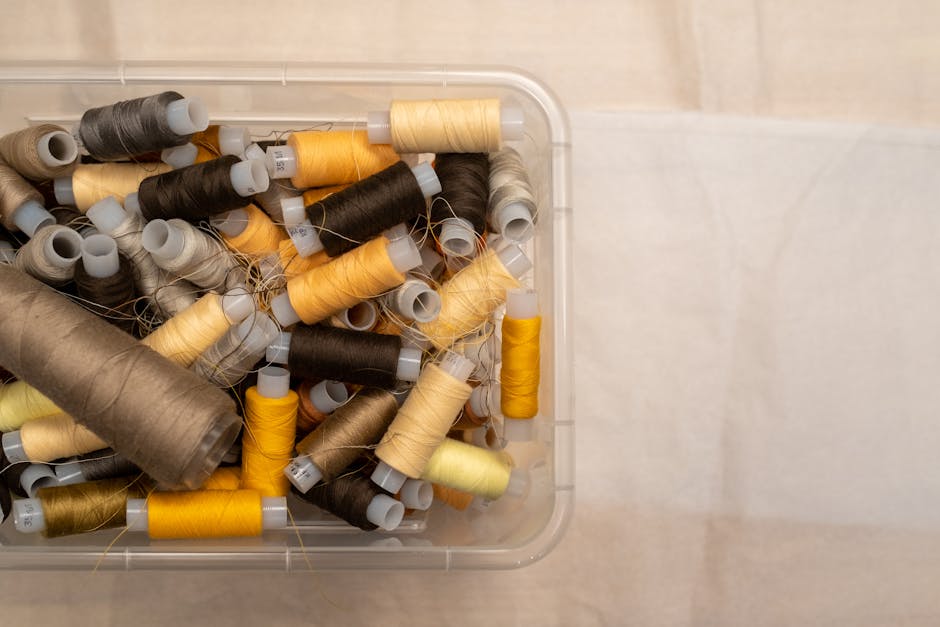 A bird's-eye view of various colored sewing threads neatly stored in a plastic box.