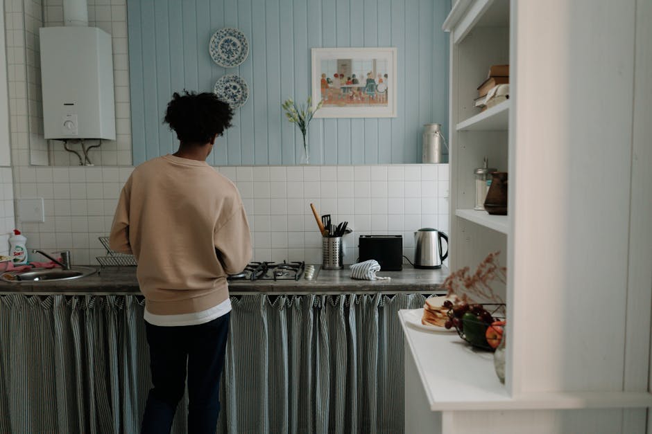 A man with afro hair cooking alone in a stylish, serene kitchen setting.