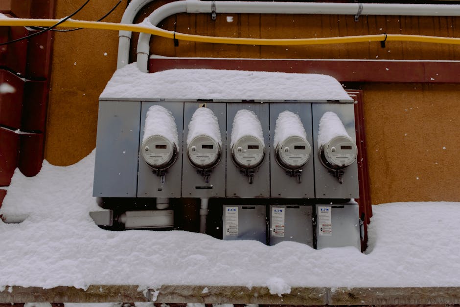 A row of electric meters covered in snow during winter, illustrating infrastructure resilience.