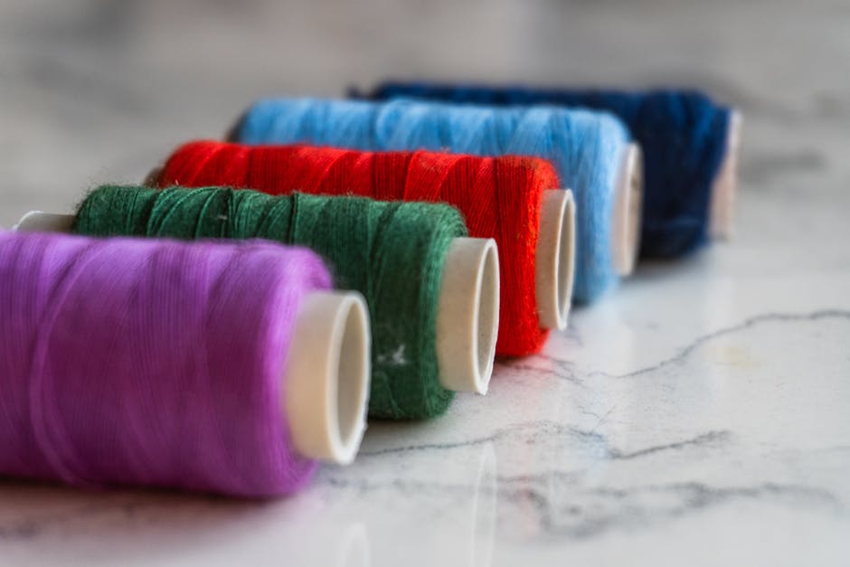 Vibrant spools of thread in various colors arranged on a marble surface in Oghuz, Azerbaijan.