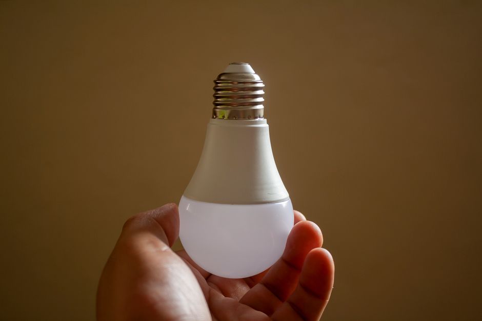 Close-up of a hand holding an energy-efficient LED bulb, emphasizing sustainability and innovation.