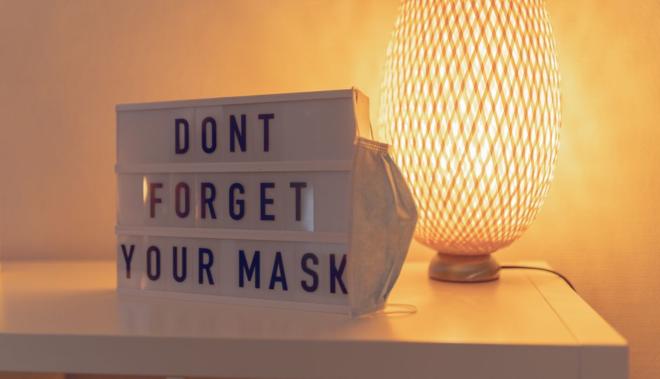 Close-up of an illuminated desk lamp and mask reminder text box.