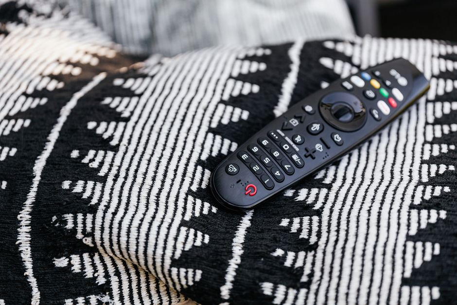 A black remote control resting on a monochrome patterned blanket, emphasizing modern home comfort.