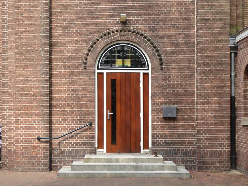 A classic wooden door with a brick archway, showcasing traditional architecture.