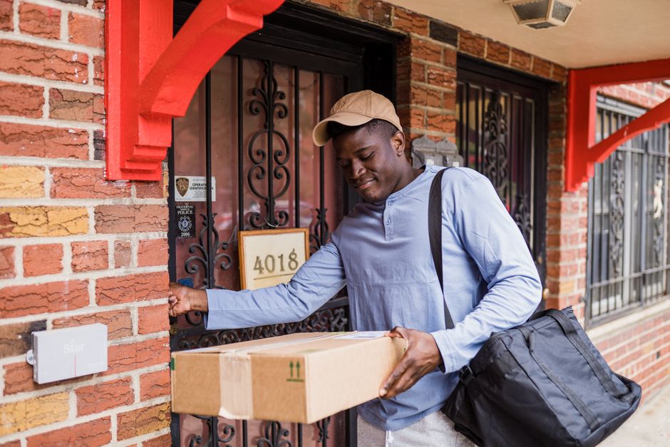 A courier delivers a package to a residential front door, emphasizing modern home delivery services.