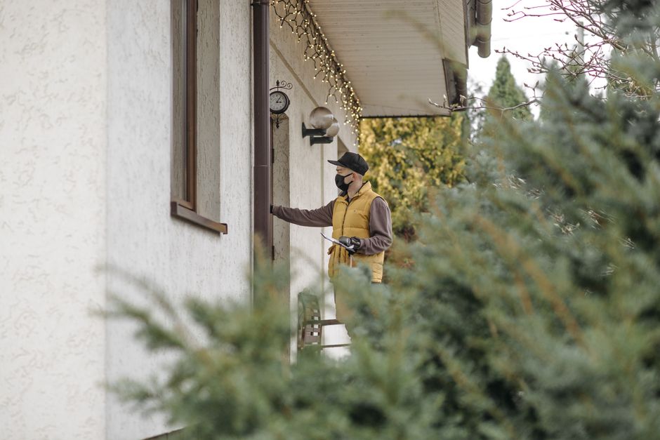 A courier in a mask delivers a package at a home entrance, captured amidst a wintery backdrop.