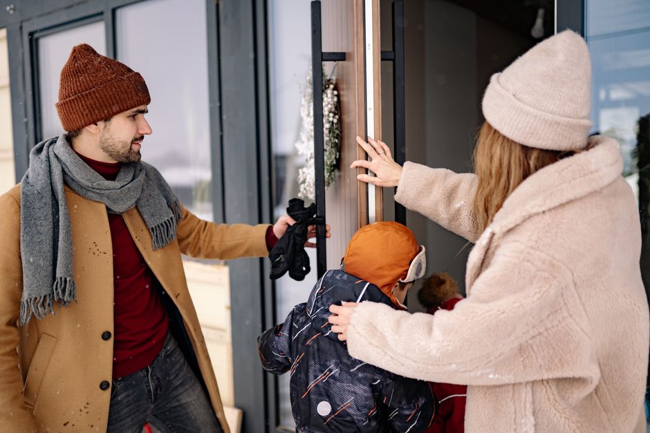 A family entering a warm home together, dressed for winter with cozy clothing.