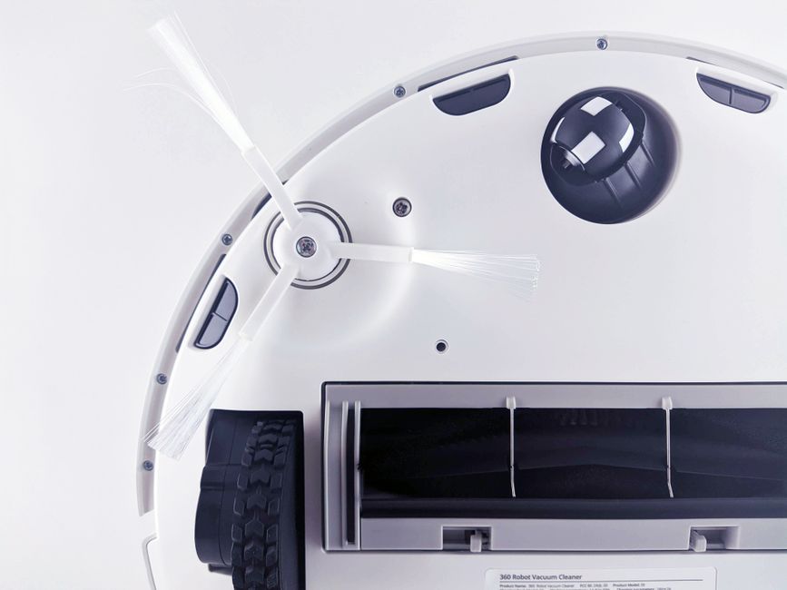 Close-up of a modern robotic vacuum cleaner underside showing brushes and components.