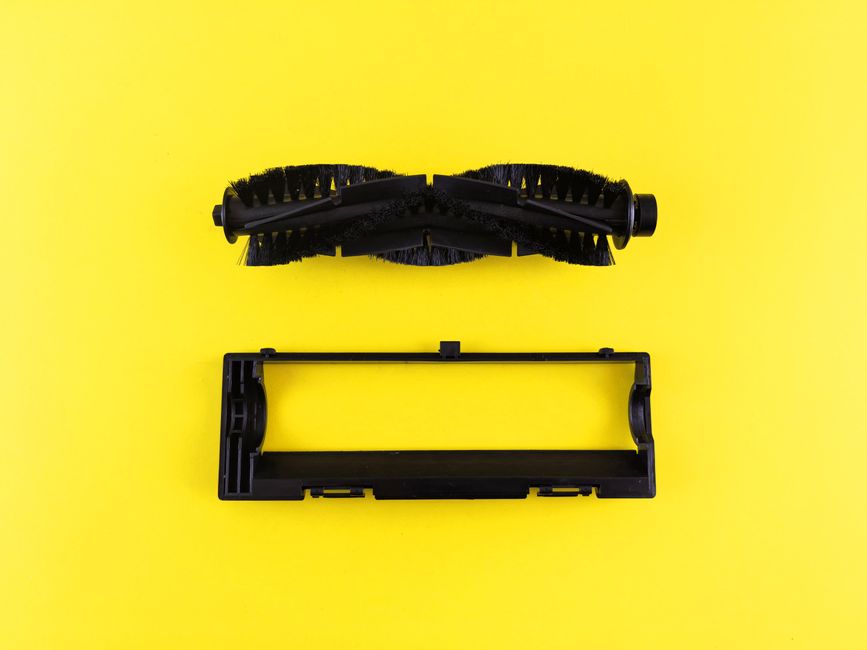 Close-up of vacuum cleaner components on vibrant yellow surface, highlighting maintenance and cleaning.