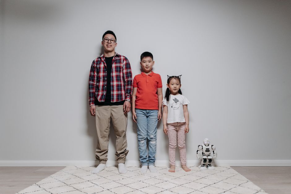 Father and children enjoying quality time with a robot. Indoor family bonding moment.