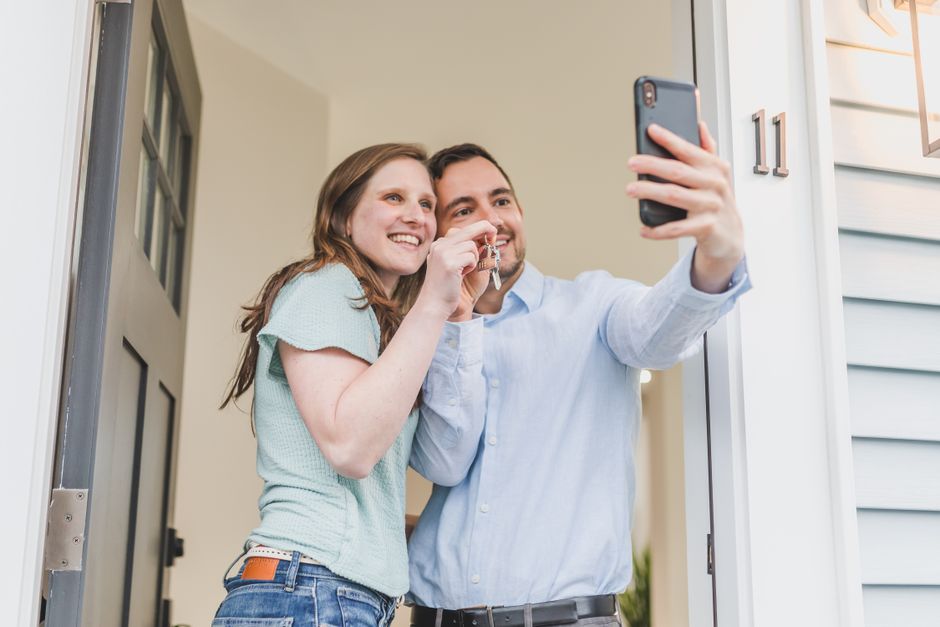 Happy couple takes a selfie while celebrating keys to their new home.