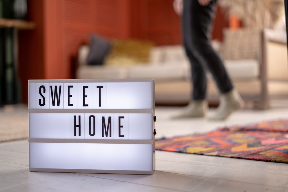 Modern living room with illuminated 'Sweet Home' sign and cozy decor.