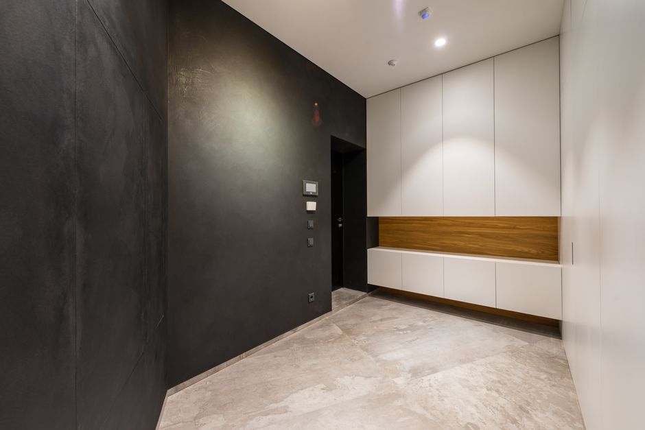 Modern room interior with white closet against black walls at home with tiled floor under glowing lamp