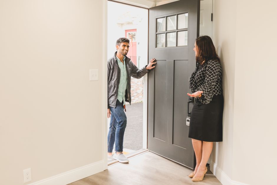 Real estate agent greeting a client at the entrance of a new home, symbolizing a welcoming embrace for potential buyers.