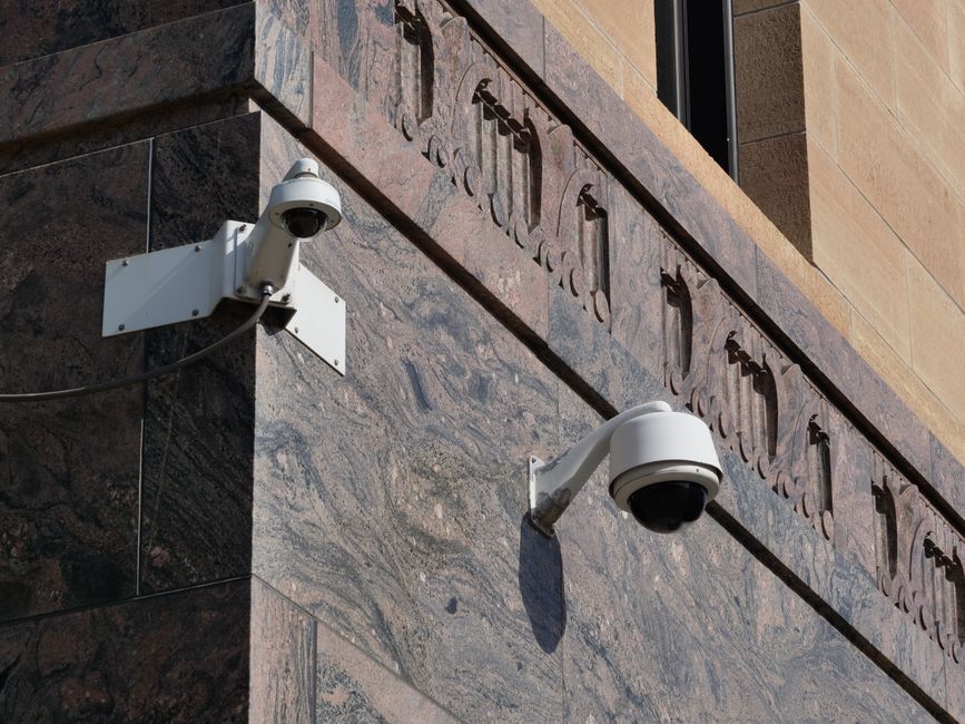 Surveillance cameras mounted on the ornate corner of a city building, ensuring security.